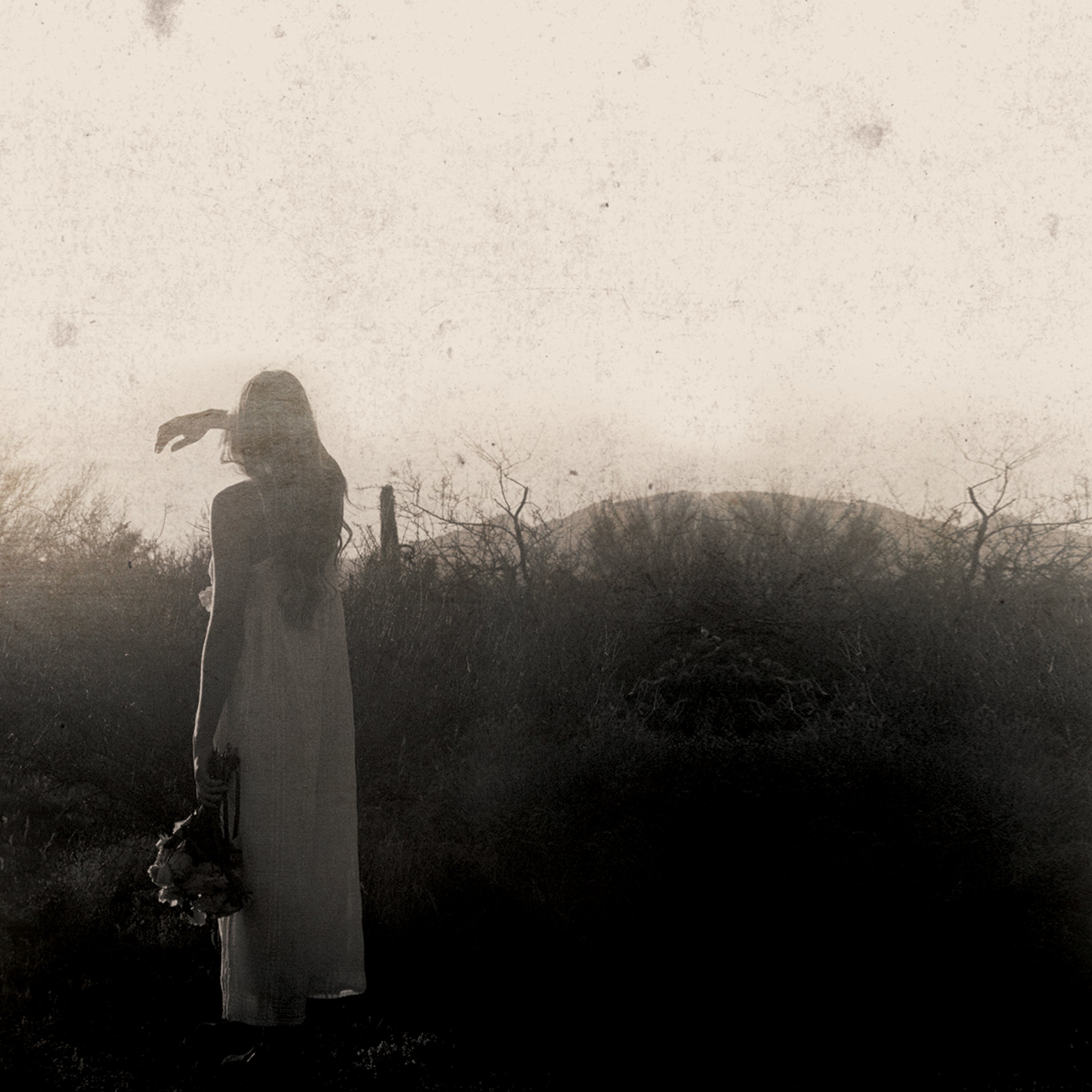 Sepia colored image of a woman standing in the desert landscape.