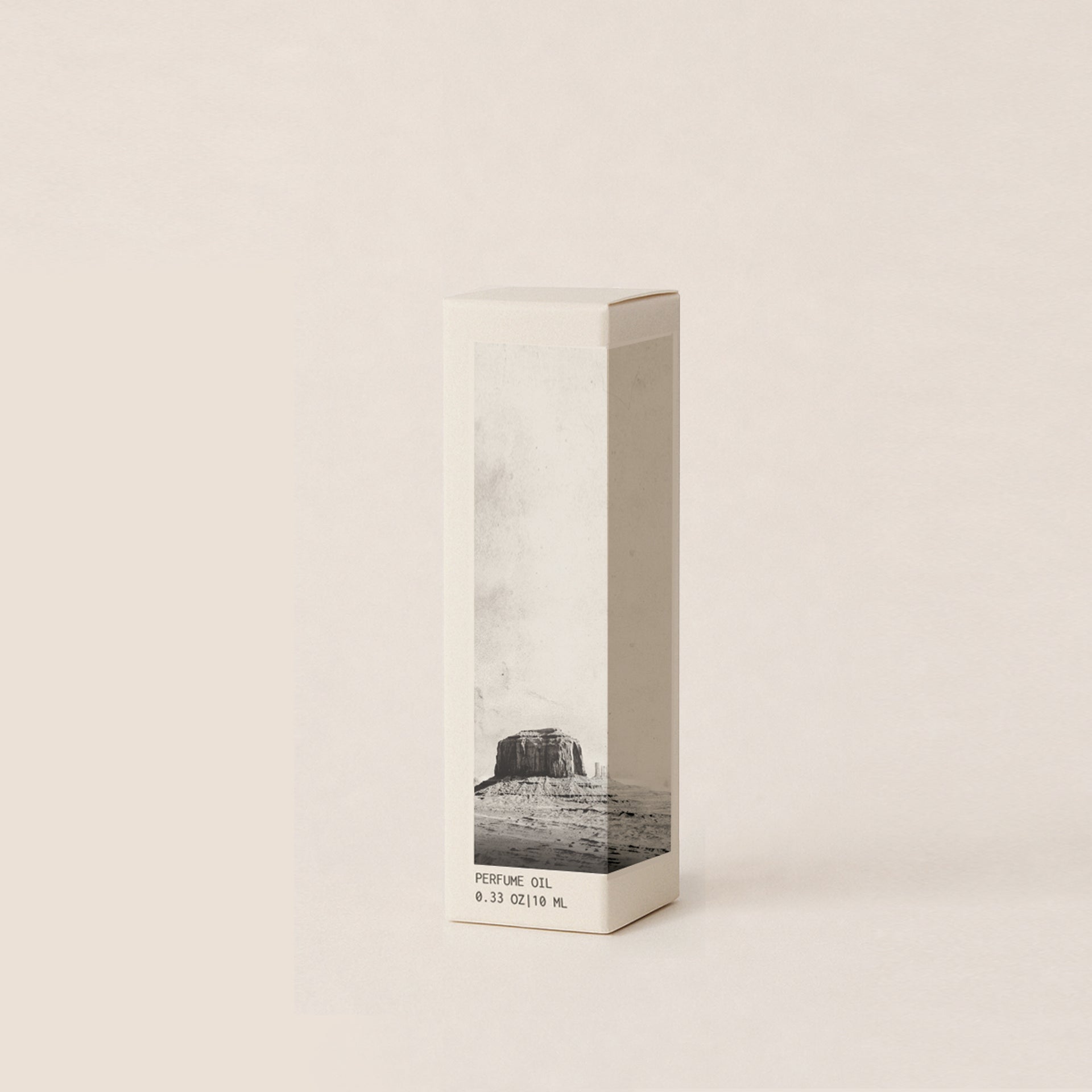 A tall, minimalist rectangular box for perfume oil, featuring a black and white landscape photograph of a mesa on the lower half, set against a solid cream background.