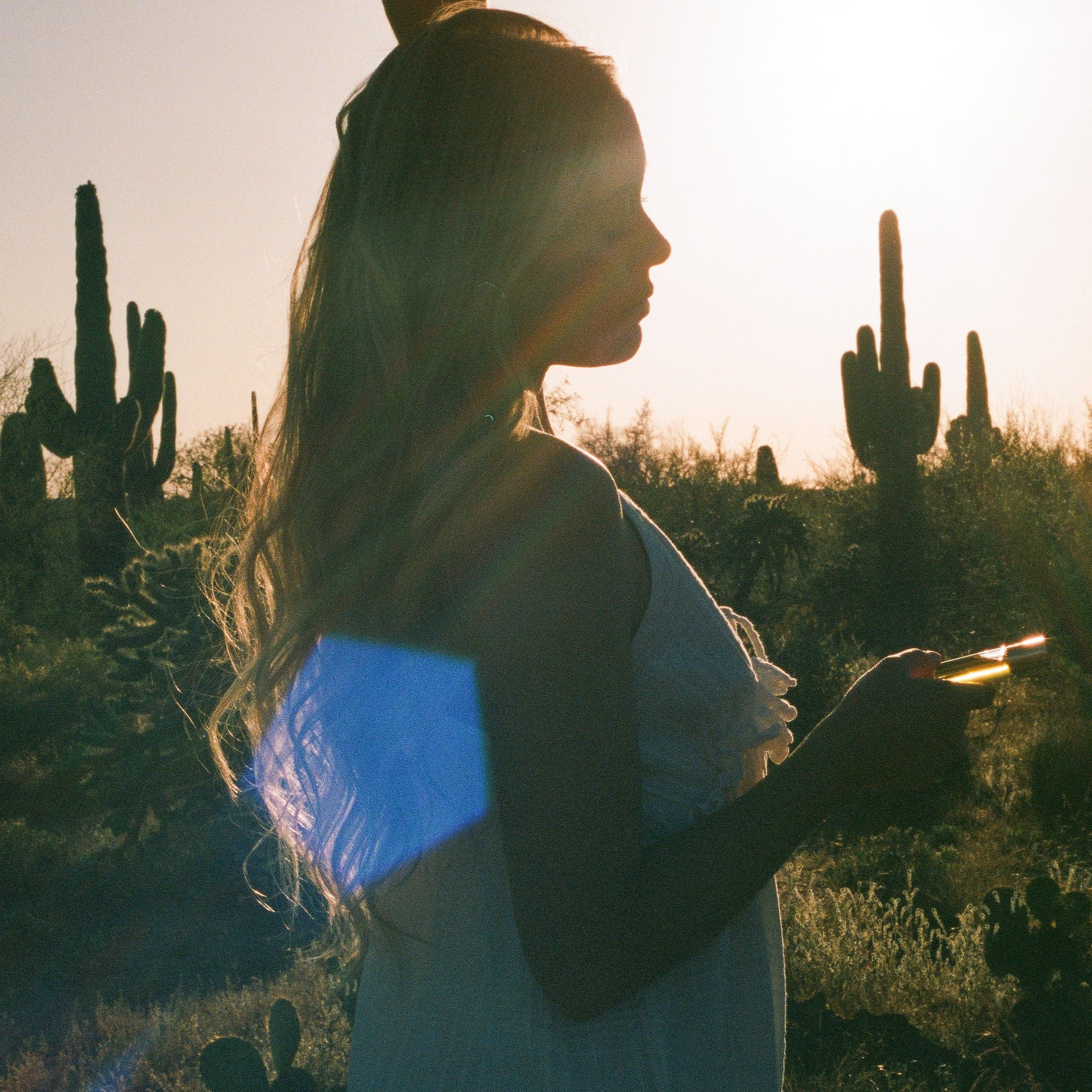 Lifestyle image of woman standing in the desert holding CICADA perfume oil.