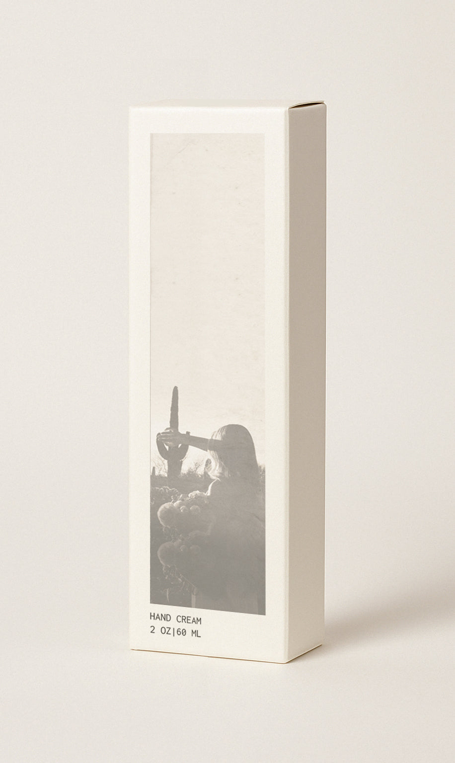 Product packaging image showing hand cream box. Box measures 2" wide x 1.25" deep x 6.5" high. Box is cream colored with No. 05 scent image on it which is an image of a woman int he desert. Box also has the text 'HAND CREAM 2 oz | 60 ml'. Image has cream colored background.