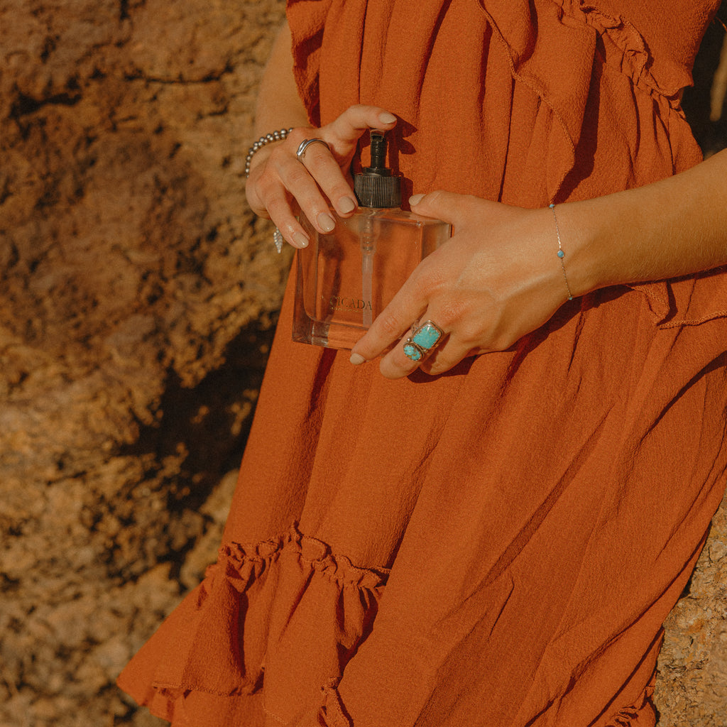 Person holding a CICADA hand soap bottle with a textured rock wall background