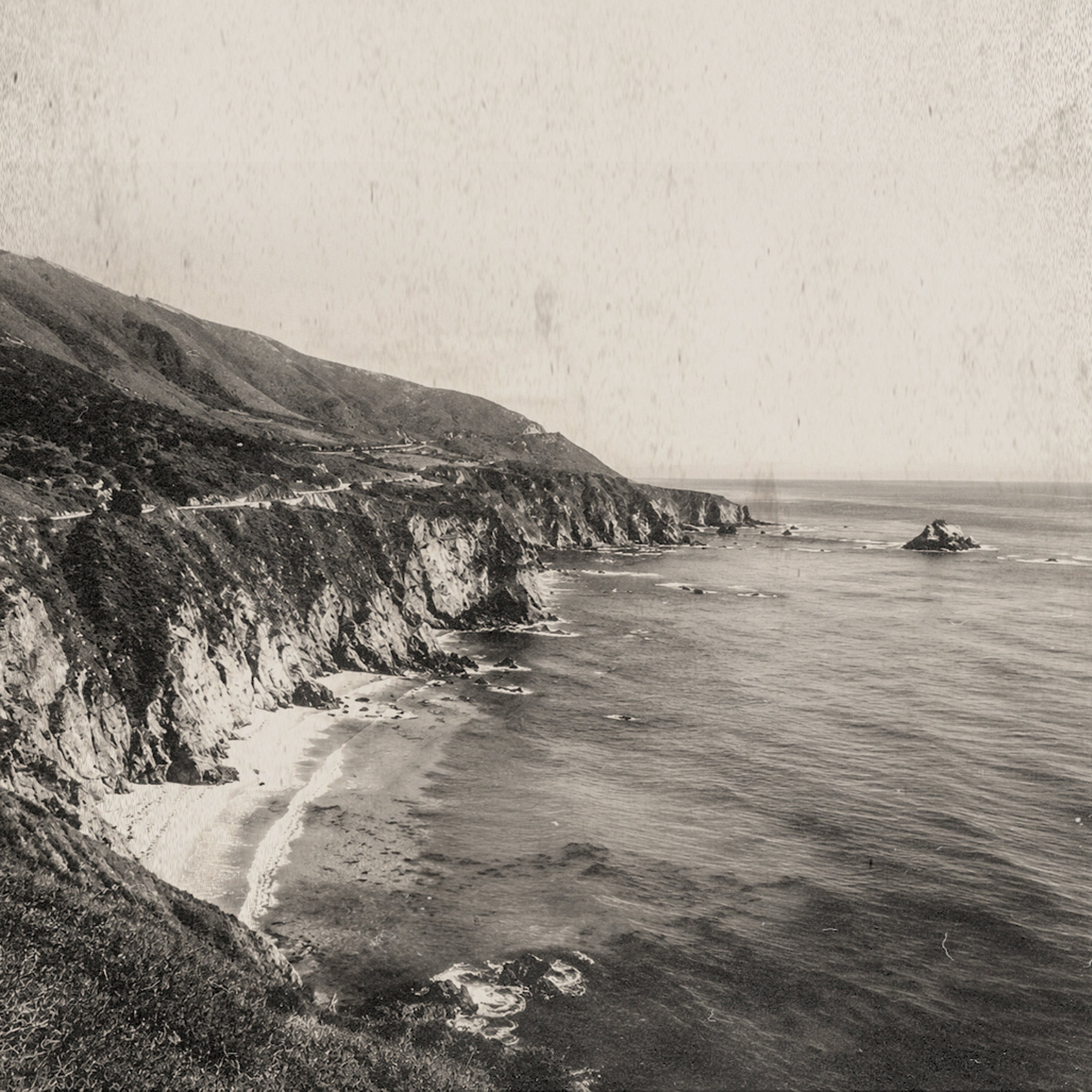 A sepia-toned coastal landscape photograph showing steep cliffs, a sandy beach, ocean water, and a small rock formation in the distance, with a vintage textured overlay.