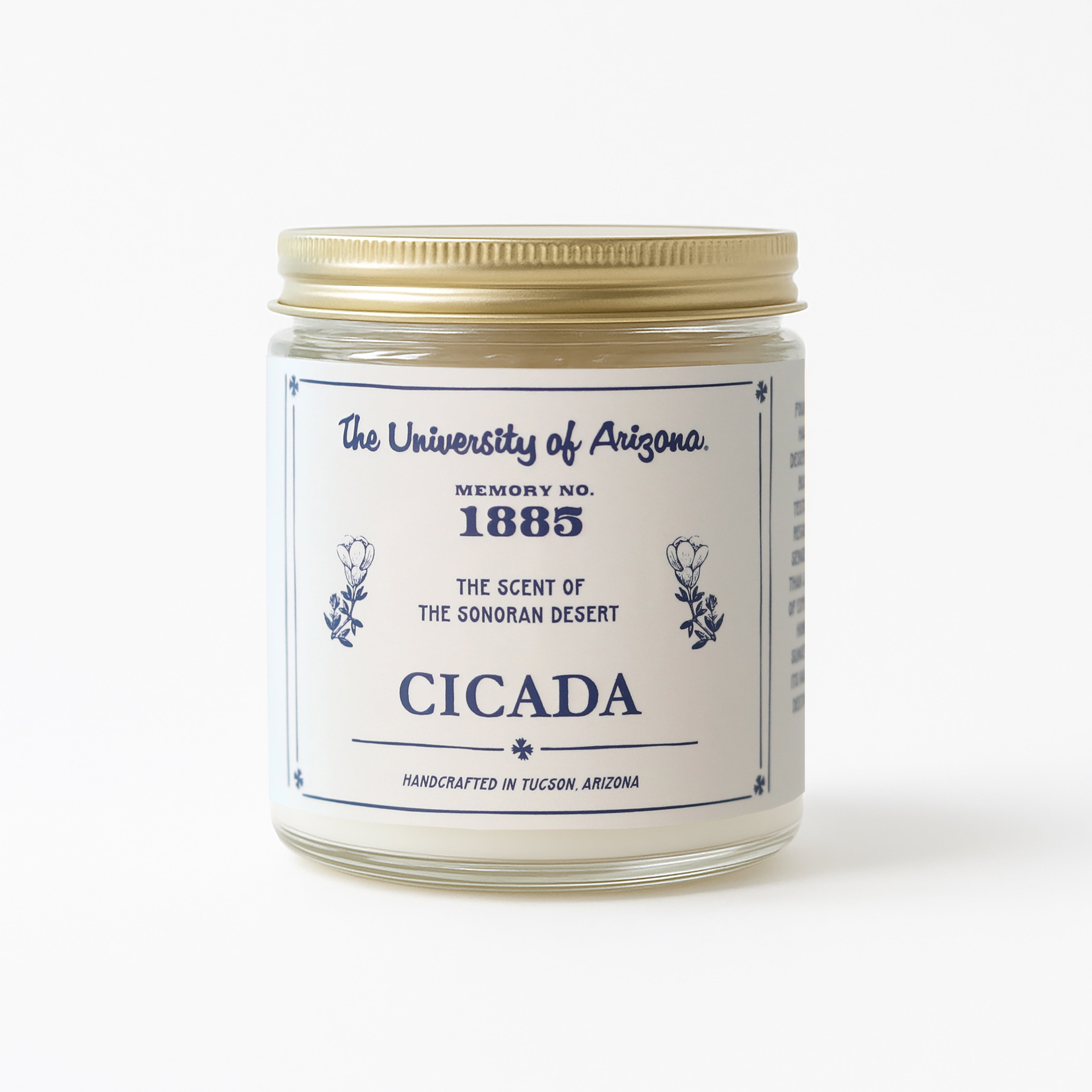 Product image showing the 7 oz Glass jar candle with gold lid with light cream label featuring 'The University of Arizona' and 'Cicada' logos on it. Label also shows No. 1885 scent name on it. Background of image is white.