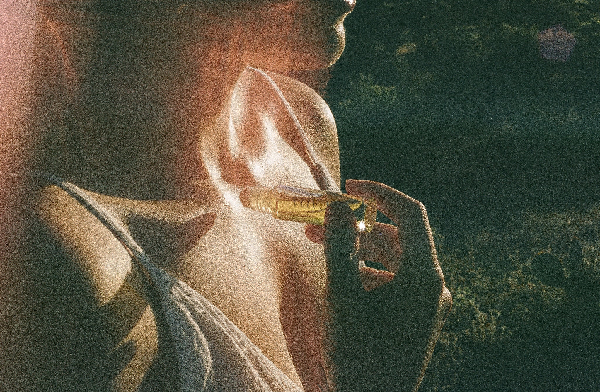 Lifestyle image of woman standing in desert applying CICADA perfume oil. 