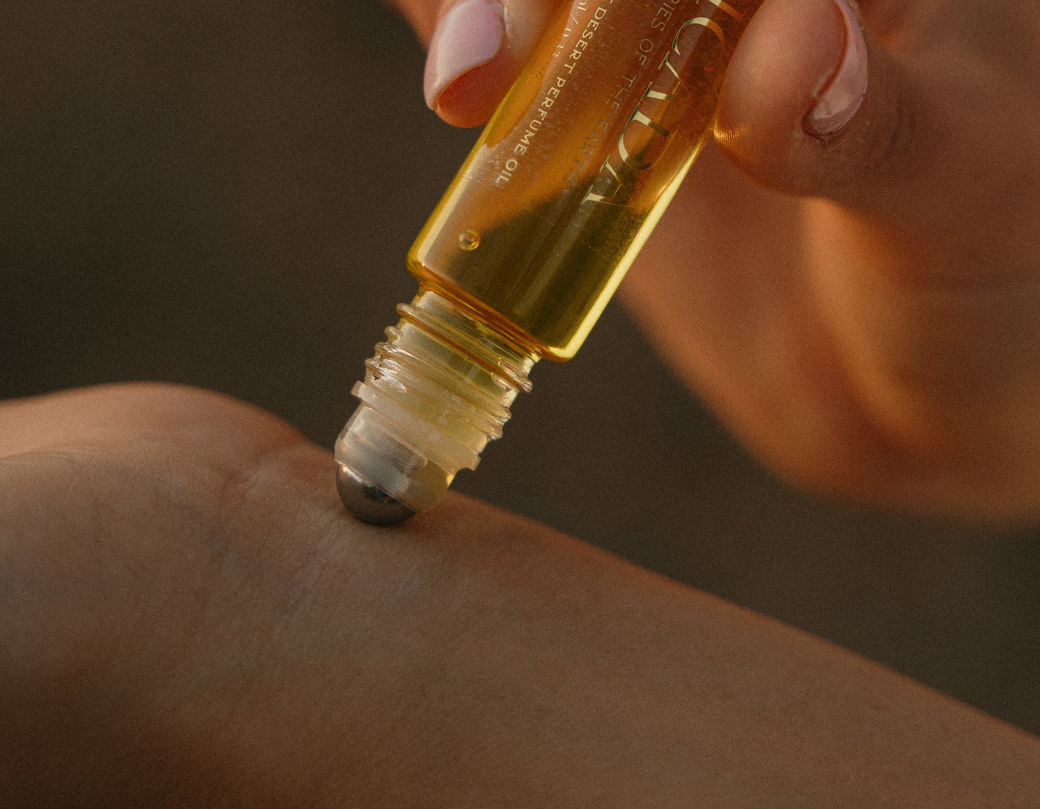 Lifestyle image of hand applying CICADA perfume oil to wrist. 