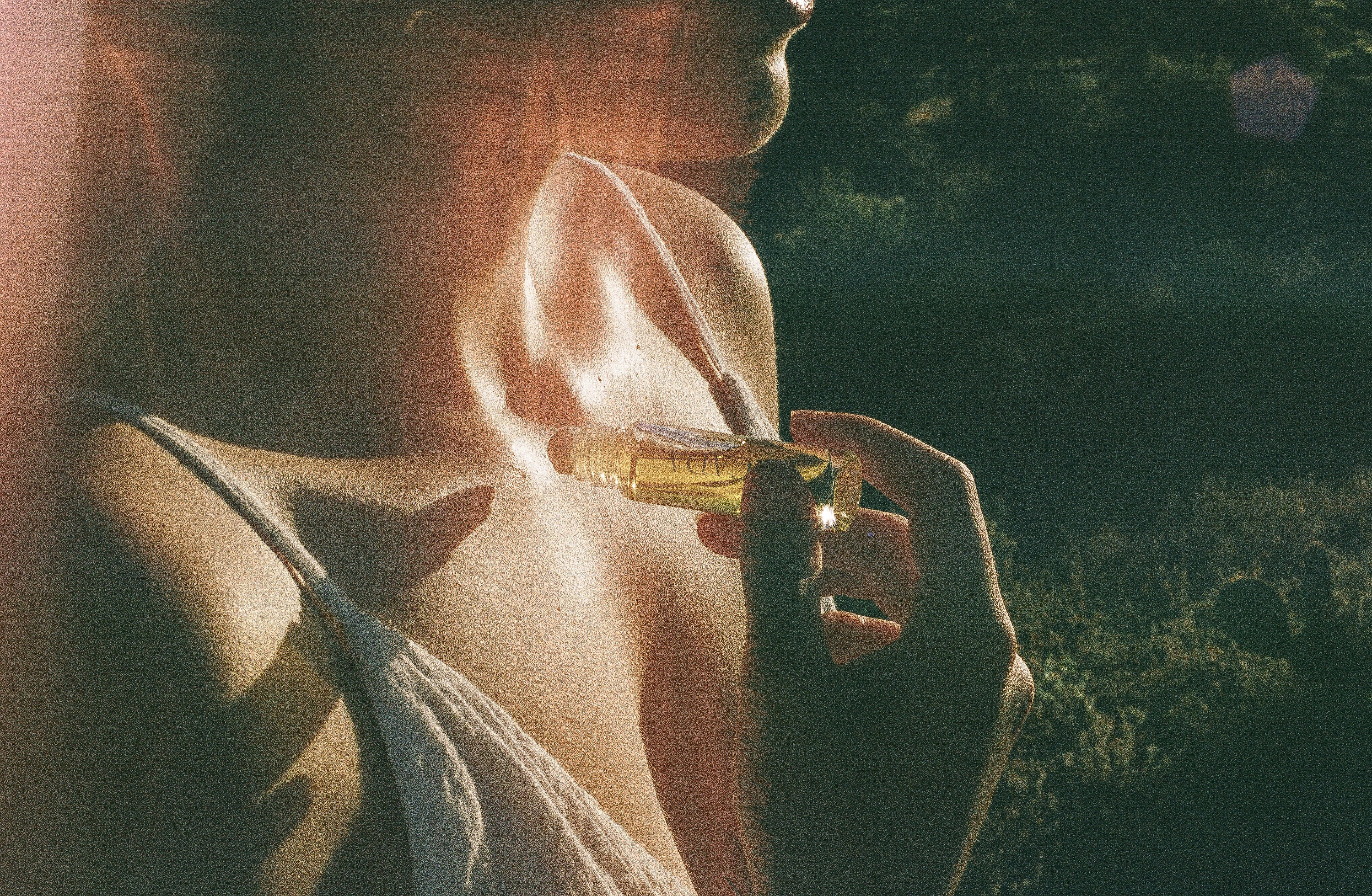 Lifestyle image of woman standing in desert applying CICADA perfume oil. 