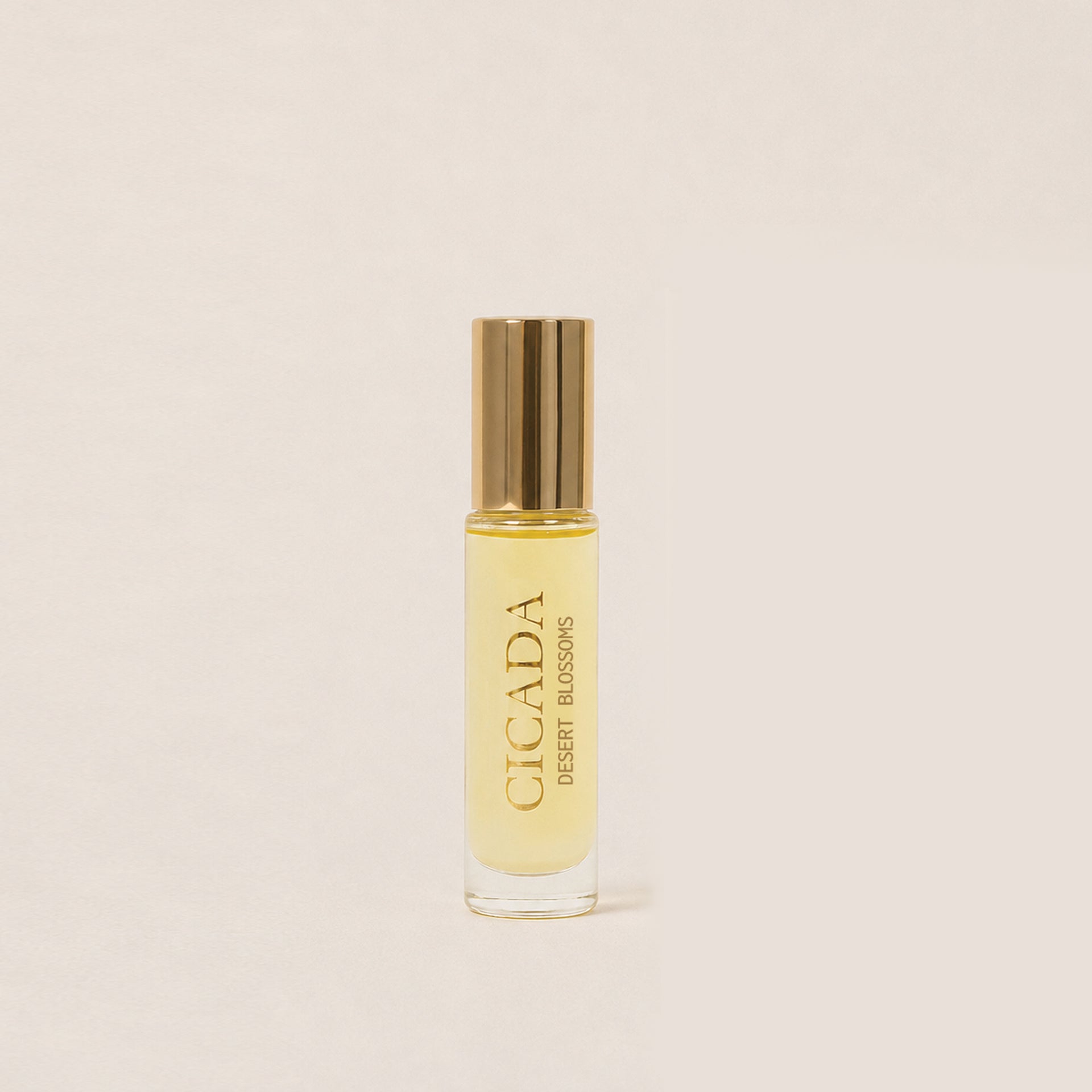 A small cylindrical glass bottle of Cicada roll-on perfume with a metallic gold cap, set against a solid light beige background.