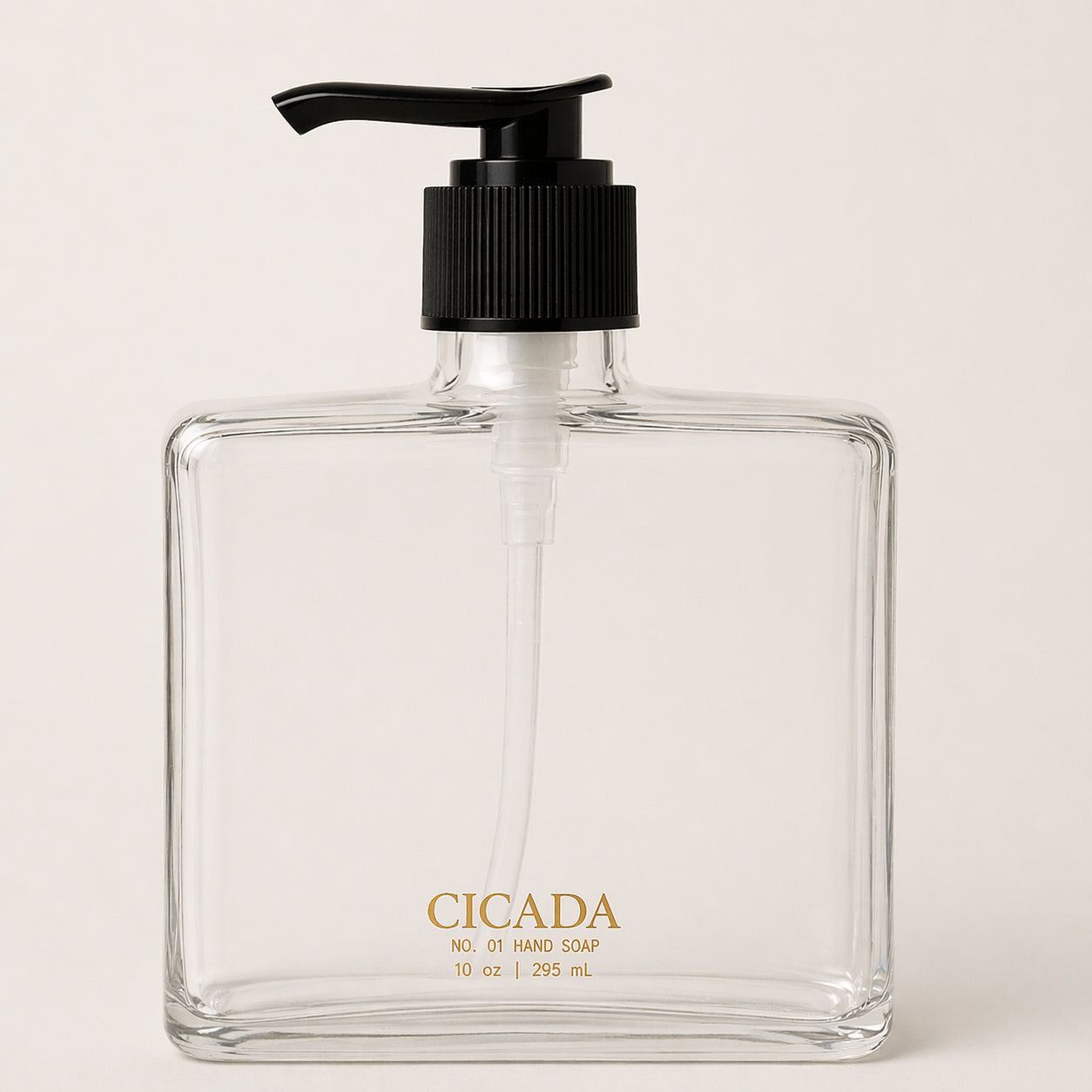 Image of clear glass hand soap bottle. Bottle is square with black pump