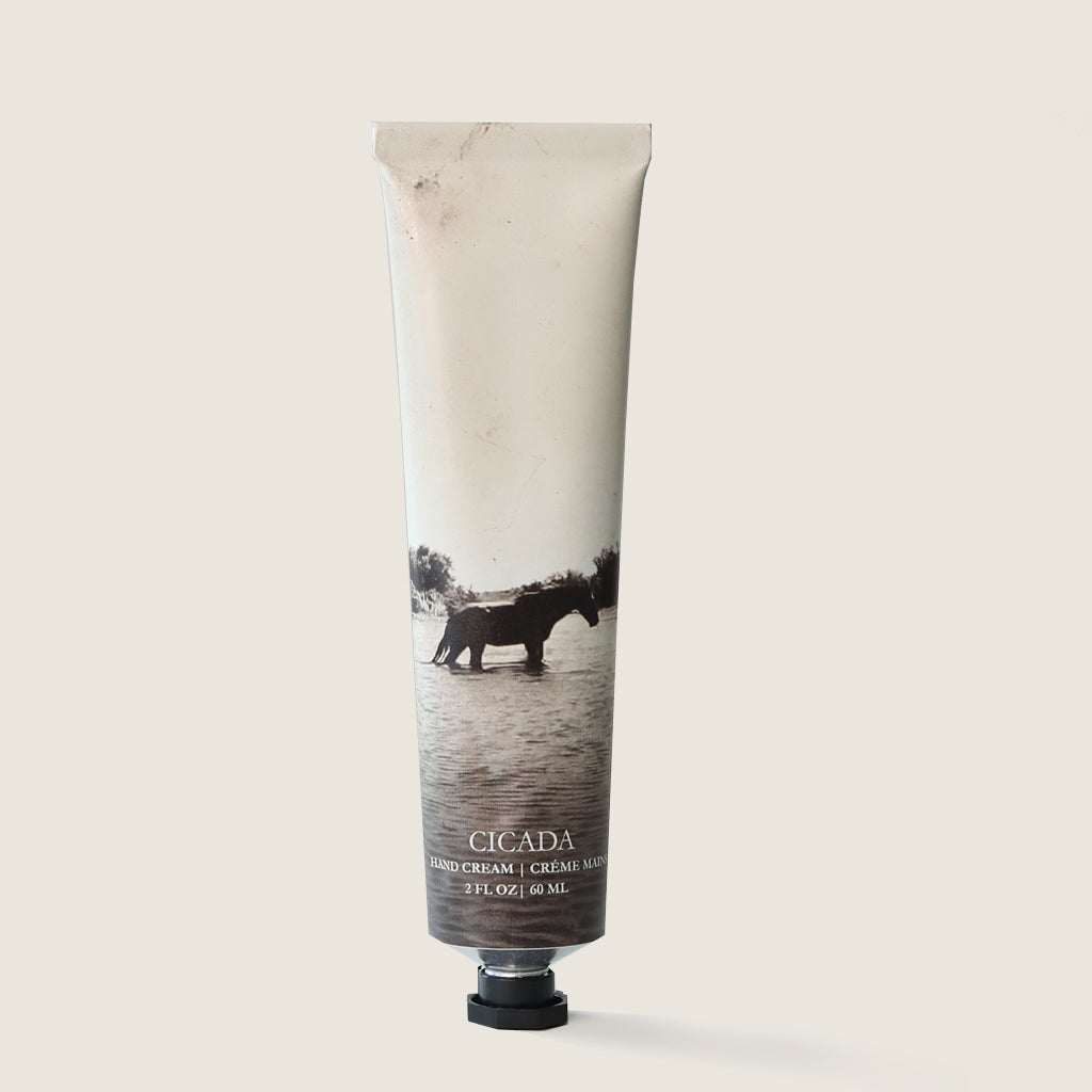 Image of Memory No 06 the scent of rivers hand cream tube. Hand Cream tube has sepia colored horse in river image on it