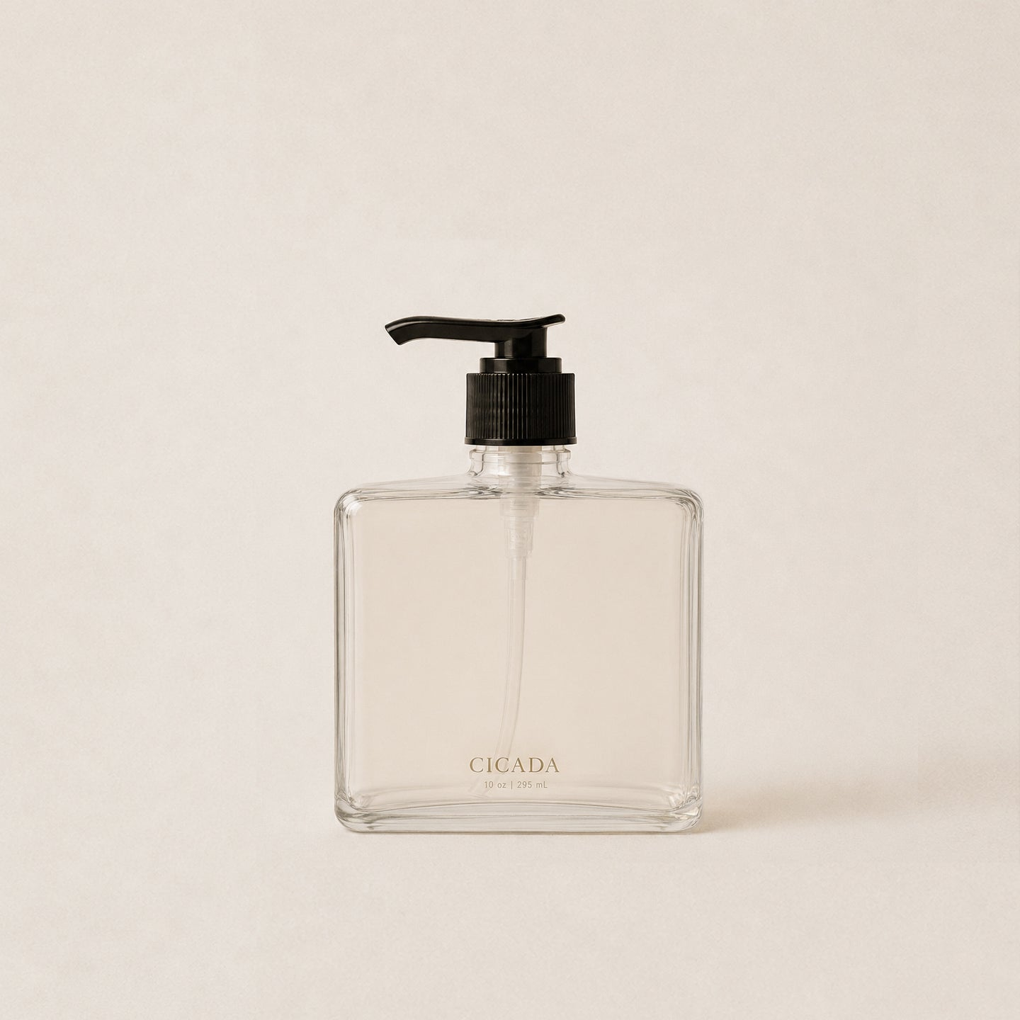Image of square glass bottle of hand wash with black pump photographed on cream background. 