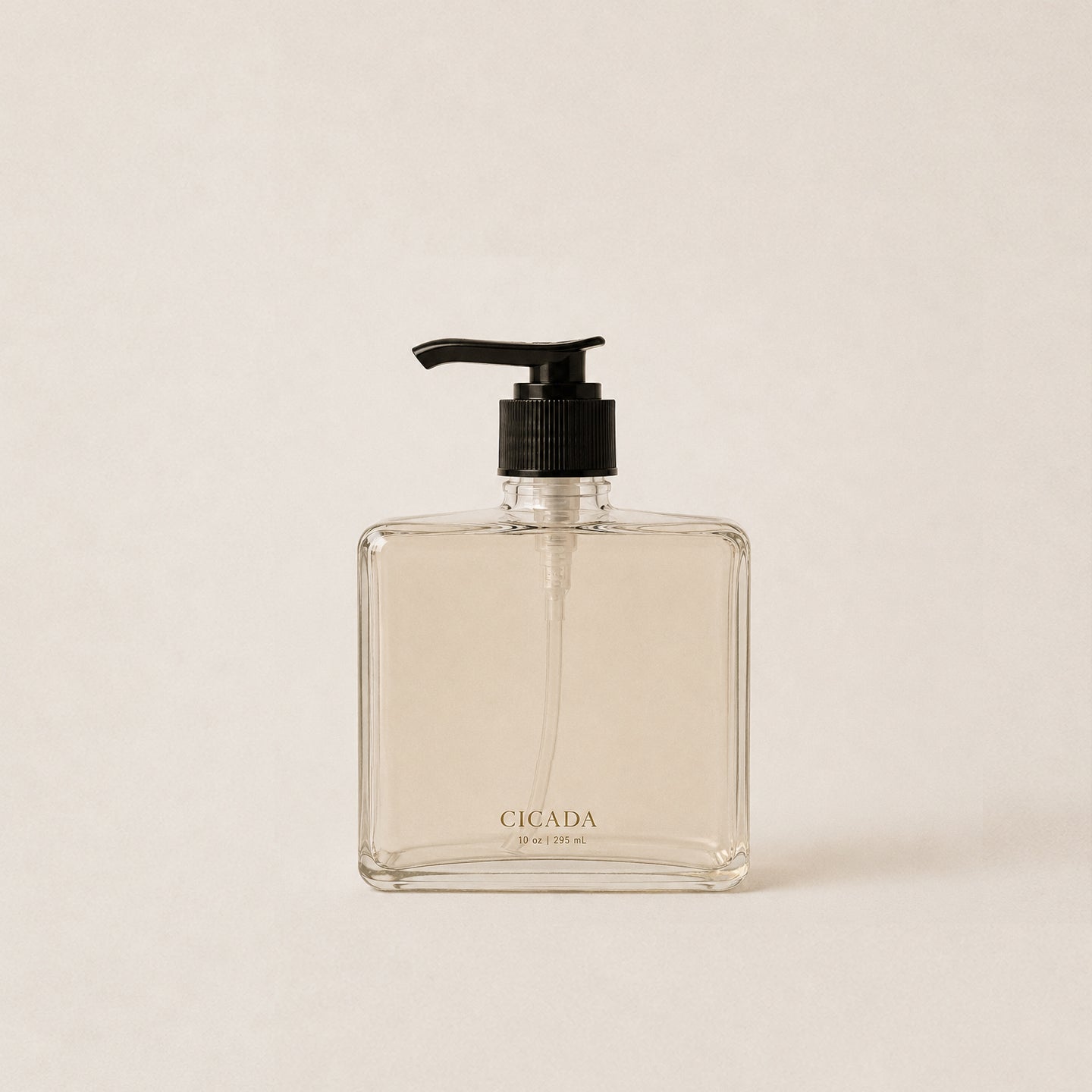 A clear glass hand soap dispenser bottle with a black pump, featuring the brand name 'CICADA' printed in gold near the bottom, set against a solid light beige background.