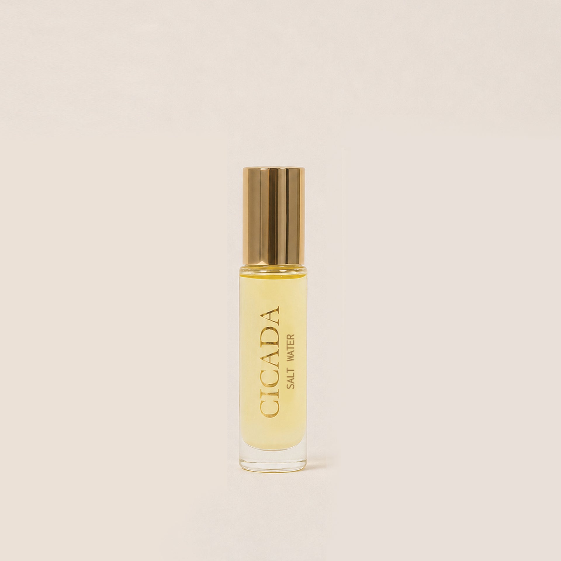 A small clear glass bottle of Cicada Salt Water Perfume Oil with a shiny gold cap, centered on a warm off-white background.